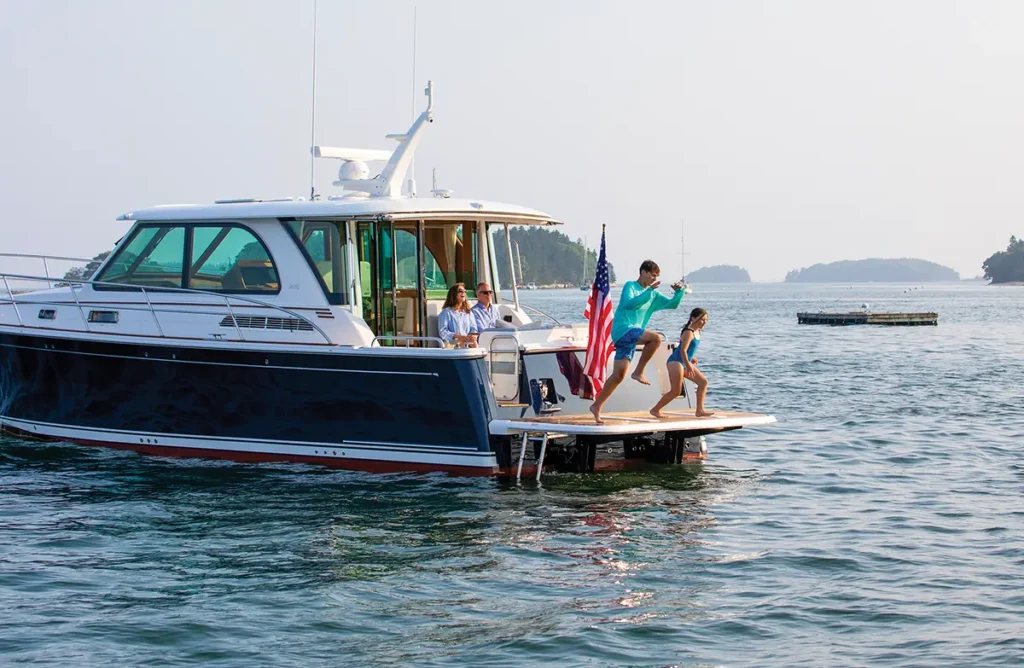 Sabre 45 Salon Express in the water with a boy jumping off the aft swim platform.