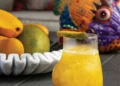 Mango pisco cocktail garnished with mango slice and microgreens
