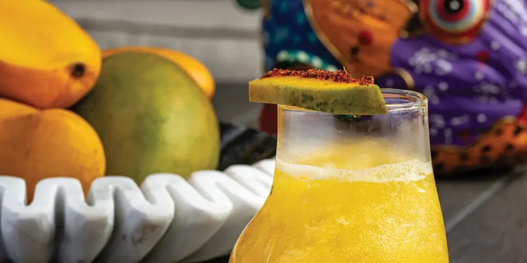 Mango pisco cocktail garnished with mango slice and microgreens