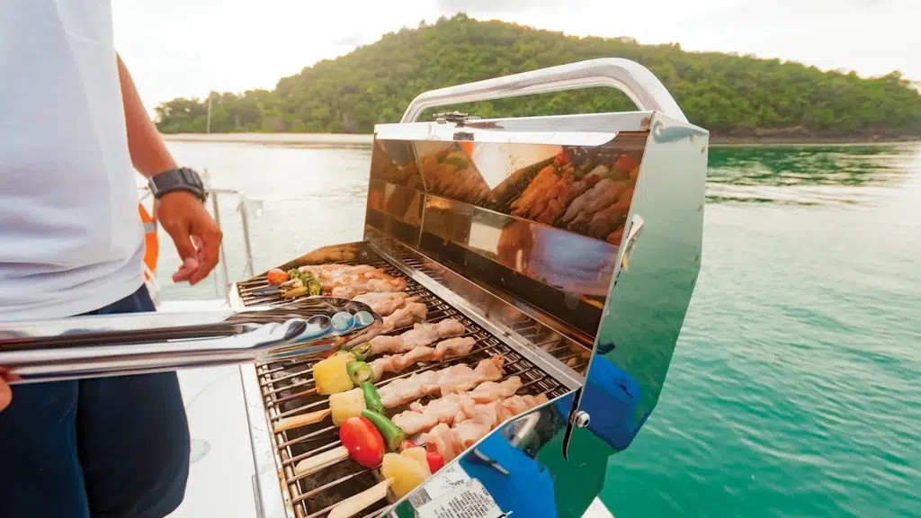 a man grilling chicken kabobs on a boat