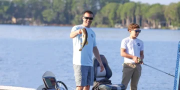An angler holds up a fish while out after using the fishing guide software
